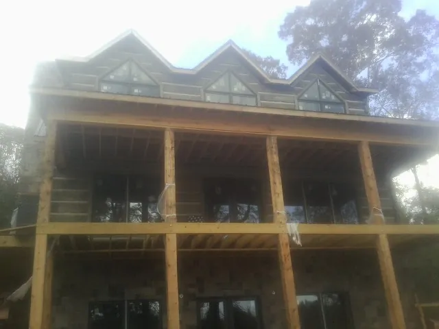 Dormers and porch framing on a large log home under construction — Roof Coating work by our crew in Gray