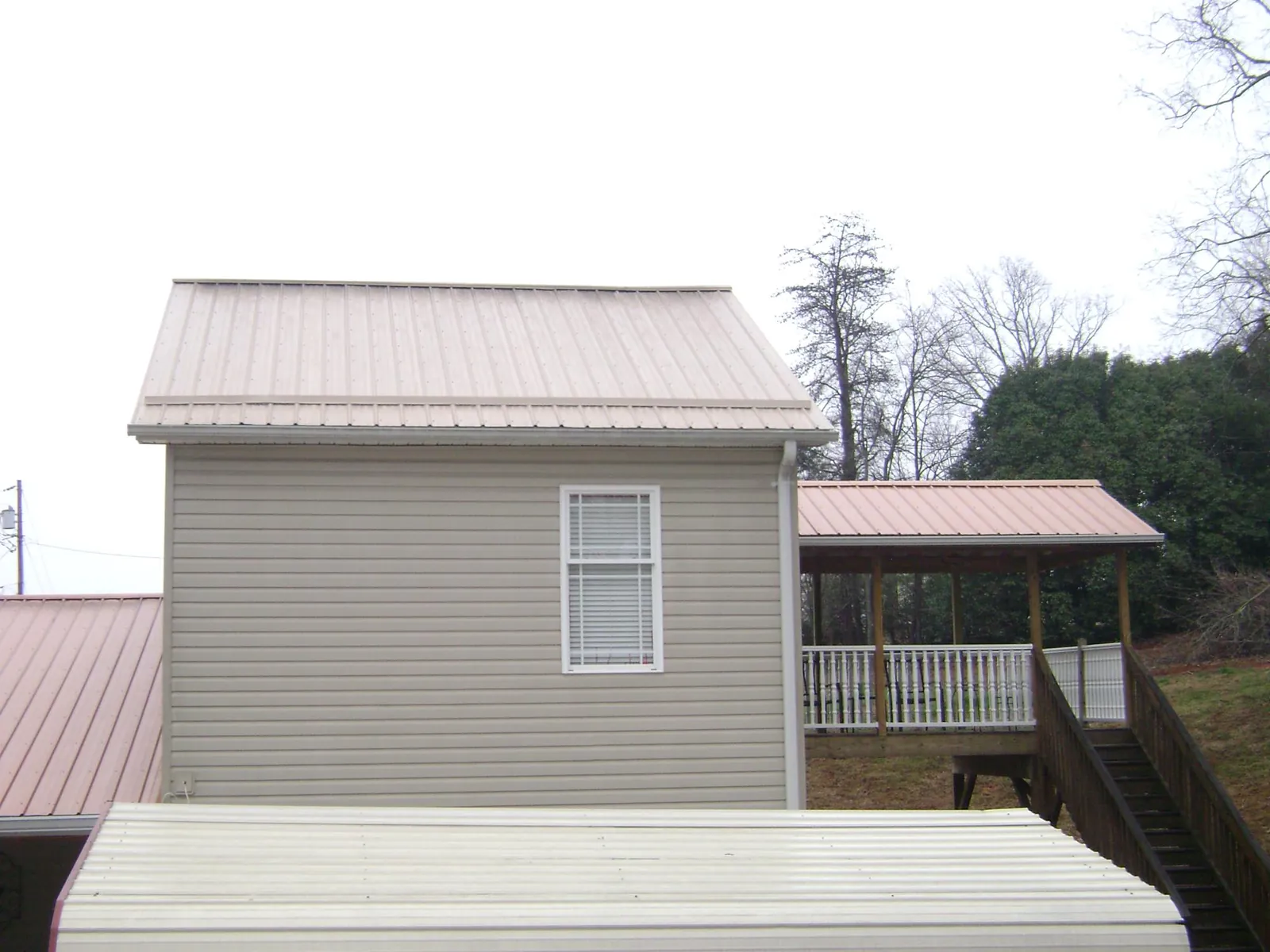 Tan metal roofs on a two story addition and attached porch, from a Roof Replacement job in Gray