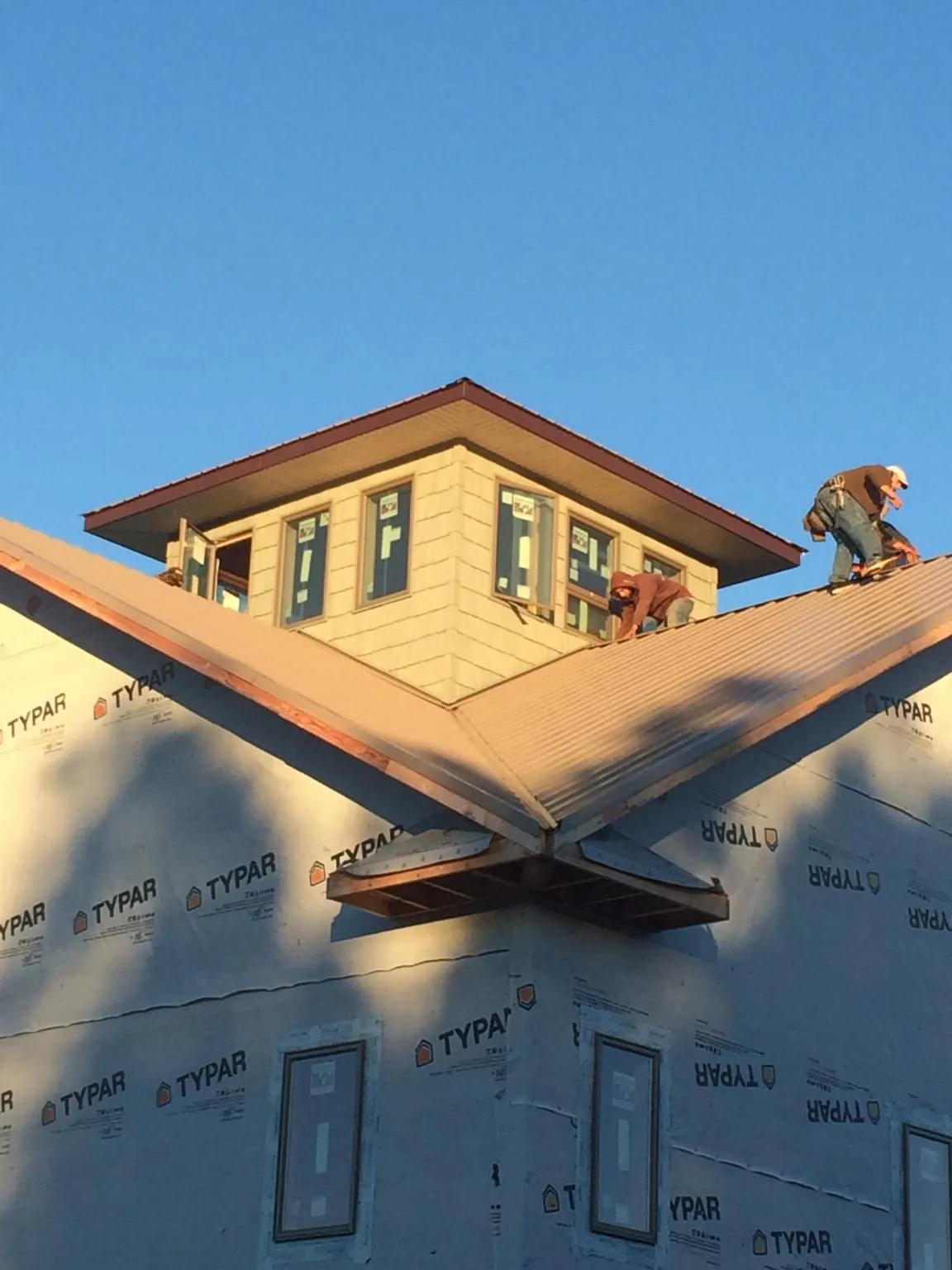Roofers working around a rooftop cupola on a new metal roof at sunset — Roof Waterproofing in Gray by Roofing Brothers